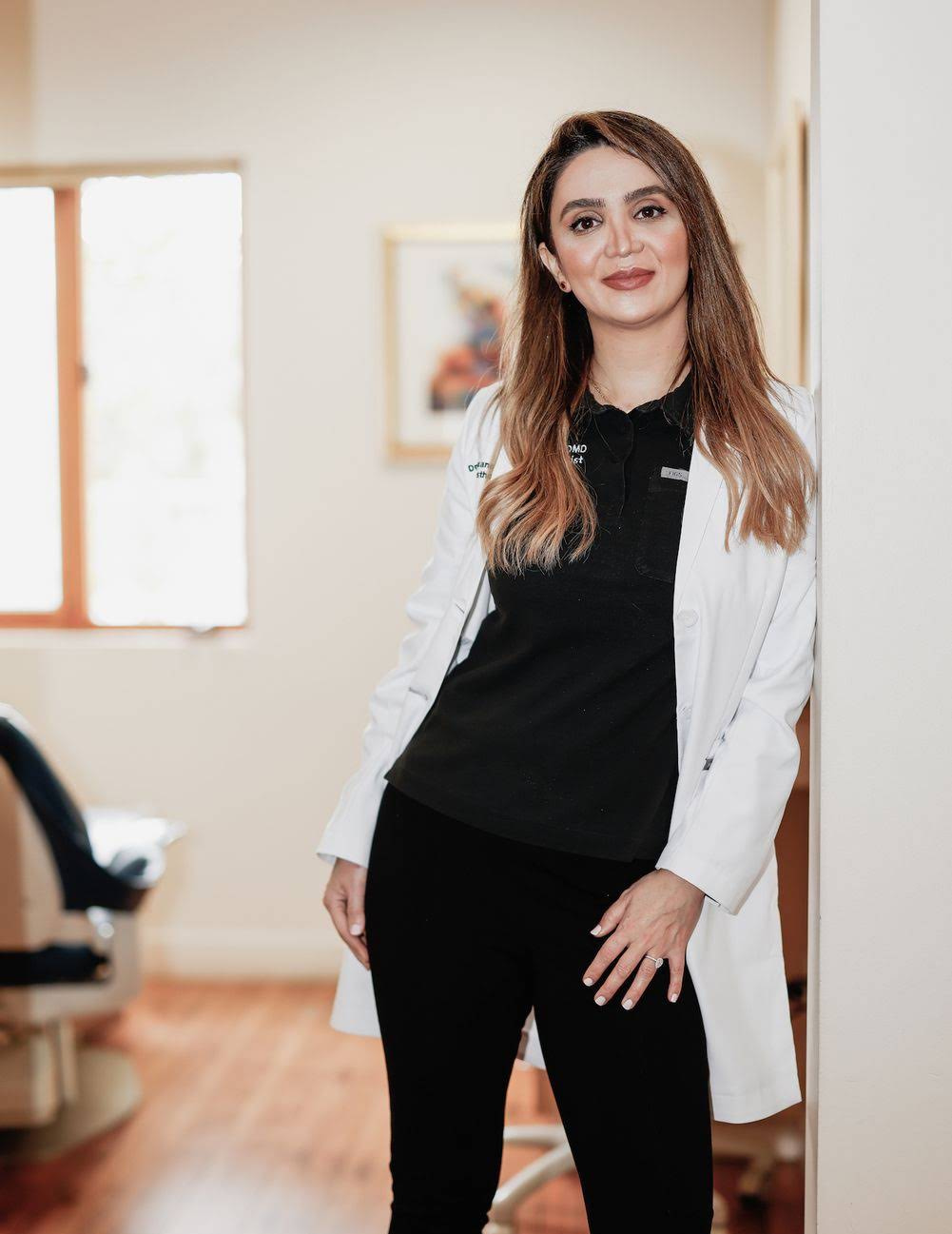 Dr. Roxanne Salavati in a white coat, standing in her Beverly Hills dental practice.