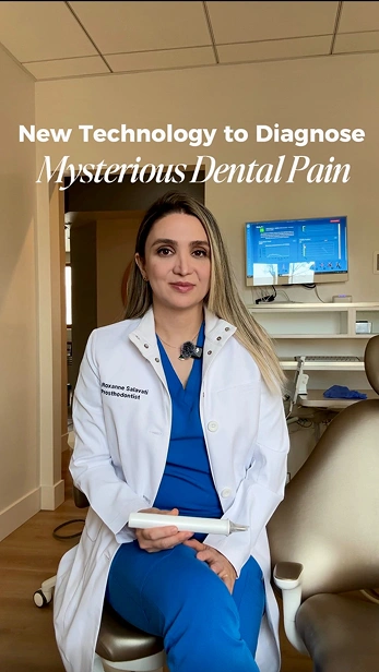 Dental professional in a white coat sitting in a dental office, representing new technology to diagnose mysterious dental pain.