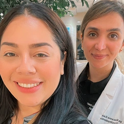 Dentist in a white coat taking a selfie with a patient outdoors, both smiling at the camera.